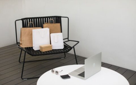 A stylish scene of online shopping with a laptop and various shopping bags on a chair.