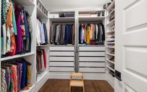 A neatly arranged walk-in closet showcasing a colorful variety of clothes and shoes.