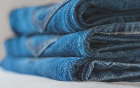 Detailed close-up image of a neat stack of blue folded denim jeans highlighting the fabric texture.