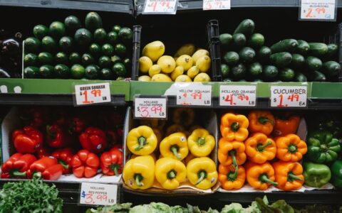 Colorful assortment of fresh vegetables at a supermarket display, highlighting peppers, squash, and cucumbers.