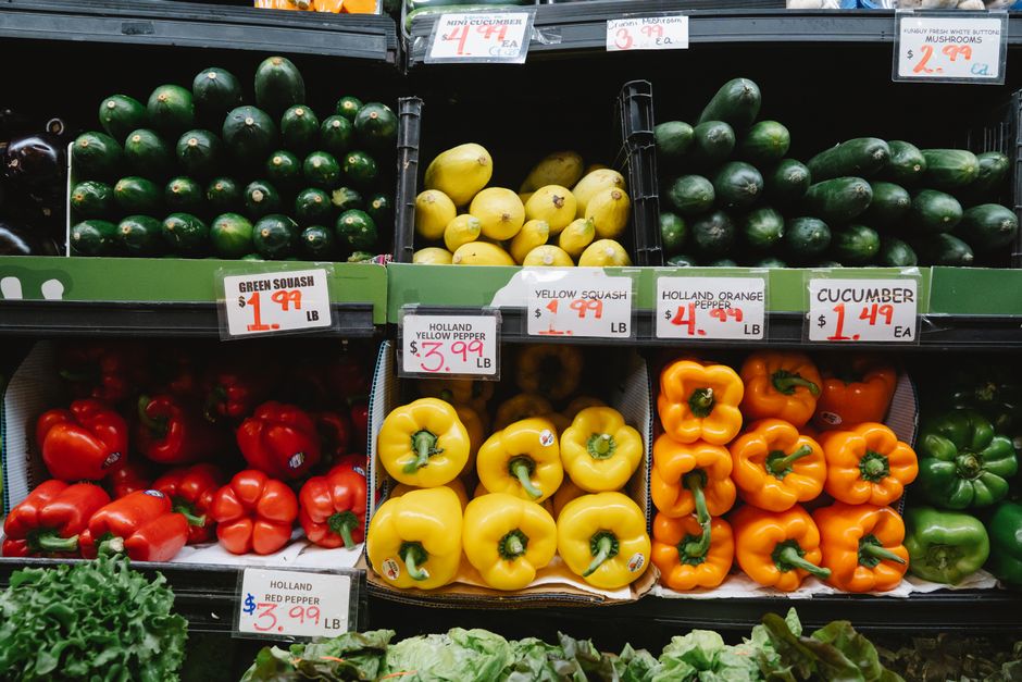 Colorful assortment of fresh vegetables at a supermarket display, highlighting peppers, squash, and cucumbers.