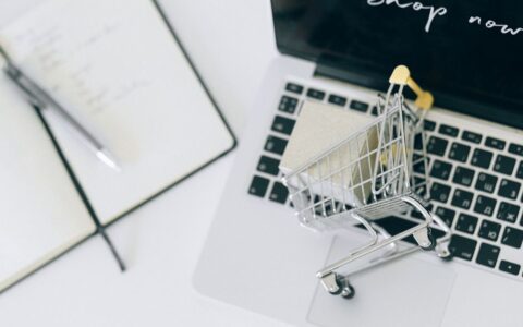 Creative depiction of online shopping with a miniature cart on a laptop keyboard.