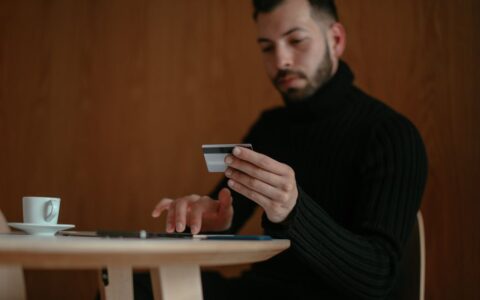 Focused man in café using tablet and credit card for online shopping.