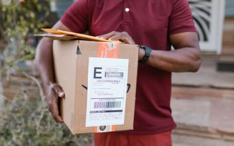 Close-up of a courier delivering a parcel with USPS express mail label outdoors.