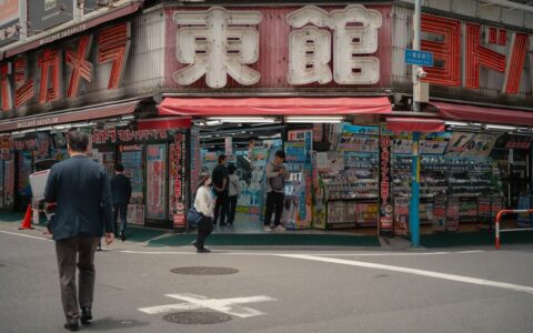 Daytime view of a busy electronics store in Tokyo with people shopping outside.
