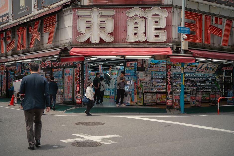 Daytime view of a busy electronics store in Tokyo with people shopping outside.